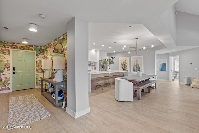 4732 S Arrow Point Dr # 304, Harrison, ID 83833 - kitchen with wallpapered walls, light wood-style floors, light countertops, a chandelier, and white cabinetry