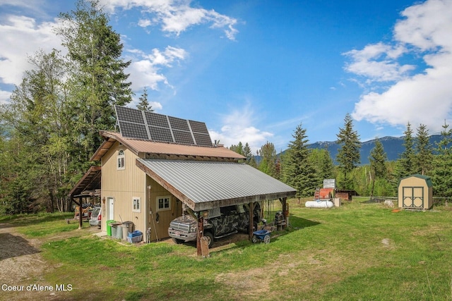 854 Two Tail Rd, Bonners Ferry, ID 83805 - rear view of property with a lawn, a storage shed, solar panels, a mountain view, and a pole building