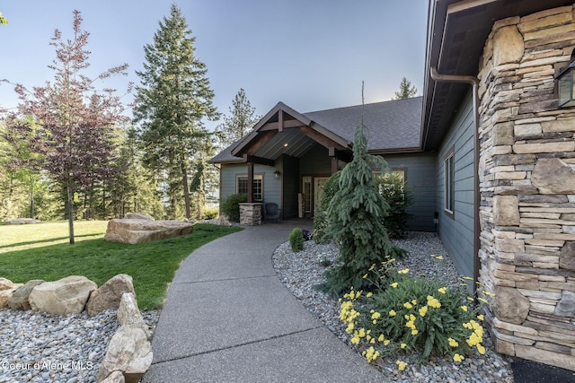 16749 W Cade Rd, Hauser, ID 83854 - view of front facade with stone siding, a shingled roof, and a front yard