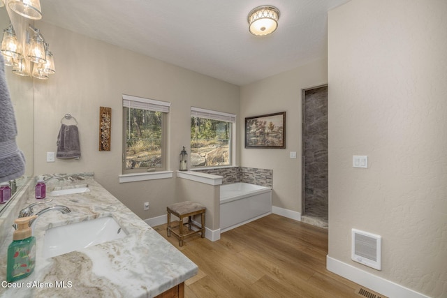 16749 W Cade Rd, Hauser, ID 83854 - full bathroom featuring a garden tub, double vanity, wood finished floors, and a chandelier