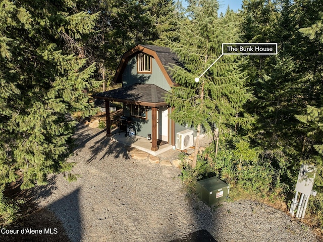 16749 W Cade Rd, Hauser, ID 83854 - view of side of home with a shingled roof, an outdoor structure, a gambrel roof, and a wooded view