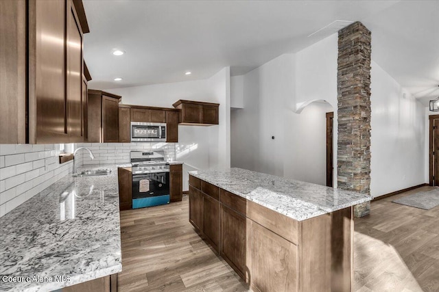 116 Prospector Lp, Kellogg, ID 83837 - kitchen with appliances with stainless steel finishes, lofted ceiling, decorative backsplash, light stone counters, and light wood-style floors