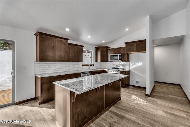 116 Prospector Lp, Kellogg, ID 83837 - kitchen with appliances with stainless steel finishes, backsplash, light wood-style floors, dark brown cabinetry, and light stone counters