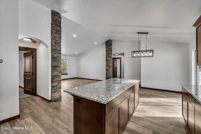 116 Prospector Lp, Kellogg, ID 83837 - kitchen featuring lofted ceiling, light wood finished floors, light stone counters, a kitchen island, and dark brown cabinets