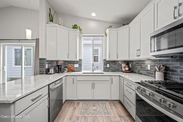 7991 N Girard Cir, Coeur Dalene, ID 83815 - kitchen featuring stainless steel appliances, vaulted ceiling, white cabinets, a peninsula, and light wood-type flooring