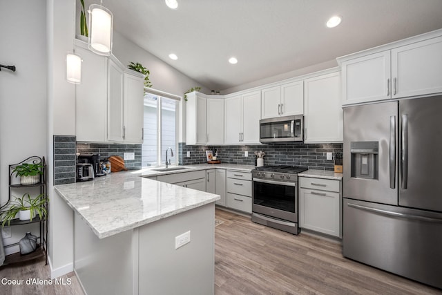 7991 N Girard Cir, Coeur Dalene, ID 83815 - kitchen with appliances with stainless steel finishes, a peninsula, backsplash, light wood-style flooring, and light stone countertops