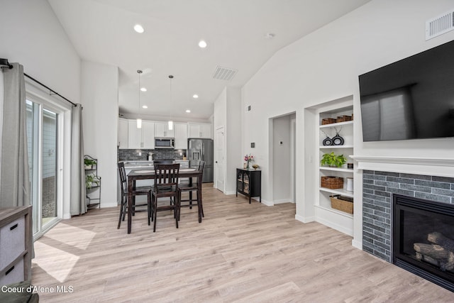 7991 N Girard Cir, Coeur Dalene, ID 83815 - dining space featuring built in shelves, light wood-style flooring, a fireplace, high vaulted ceiling, and recessed lighting