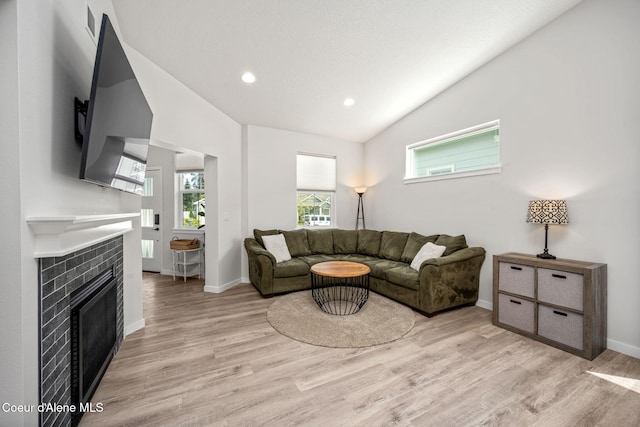 7991 N Girard Cir, Coeur Dalene, ID 83815 - living room featuring vaulted ceiling, light wood finished floors, a tiled fireplace, and recessed lighting