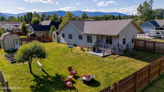 208 Brittany Loop, Sandpoint, ID 83864 - back of house featuring a storage unit, a fire pit, a deck with mountain view, and a fenced backyard