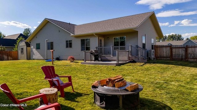 208 Brittany Loop, Sandpoint, ID 83864 - back of house with an outdoor fire pit, a fenced backyard, a wooden deck, roof with shingles, and a shed
