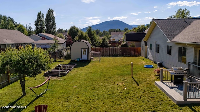 208 Brittany Loop, Sandpoint, ID 83864 - fenced backyard featuring a storage shed, a deck with mountain view, a residential view, and a vegetable garden