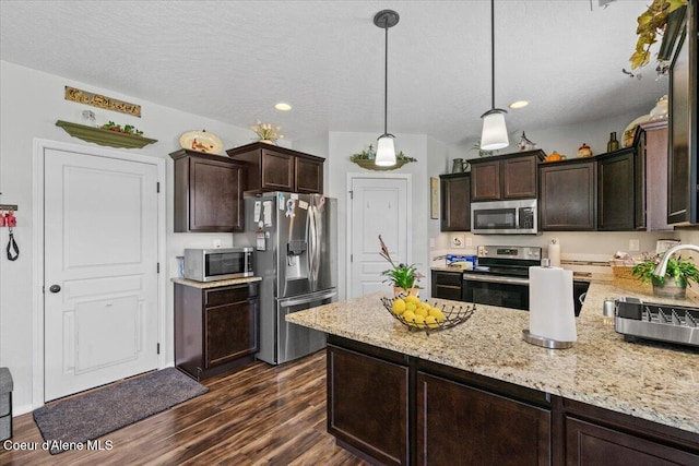 838 W Jenicek Loop, Post Falls, ID 83854 - kitchen with appliances with stainless steel finishes, dark brown cabinetry, dark wood-style flooring, light stone counters, and recessed lighting