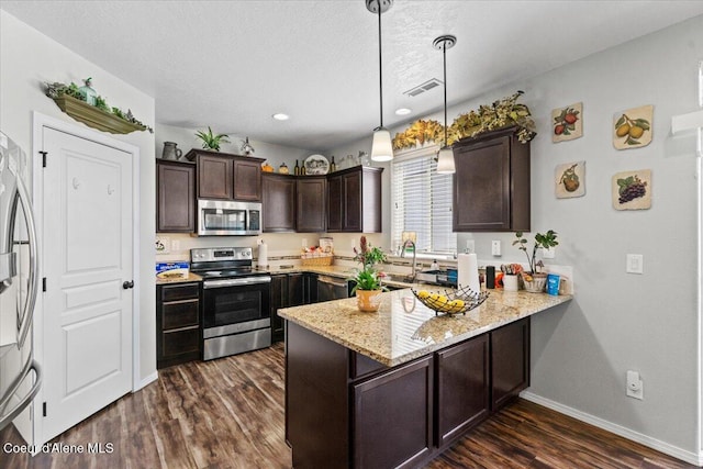 838 W Jenicek Loop, Post Falls, ID 83854 - kitchen featuring stainless steel appliances, a peninsula, dark brown cabinets, dark wood-style flooring, and light stone countertops