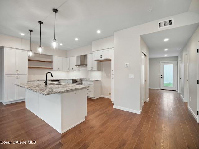 995 E Railroad Ave, Post Falls, ID 83854 - kitchen with wall chimney exhaust hood, open shelves, stainless steel range, a center island with sink, and white cabinets