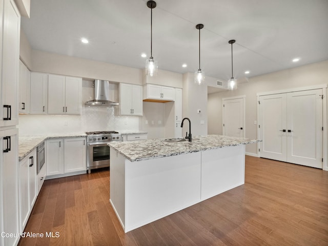 995 E Railroad Ave, Post Falls, ID 83854 - kitchen featuring wall chimney range hood, high end stainless steel range, wood finished floors, white cabinets, and recessed lighting
