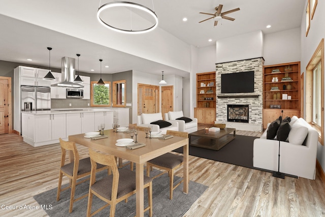 24 Bellflower, Blanchard, ID 83804 - dining room featuring light wood-style flooring, a ceiling fan, recessed lighting, a fireplace, and a towering ceiling