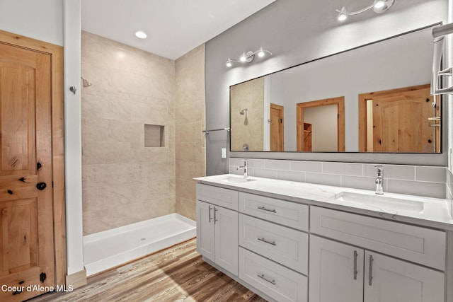 24 Bellflower, Blanchard, ID 83804 - bathroom featuring double vanity, decorative backsplash, wood finished floors, and a tile shower