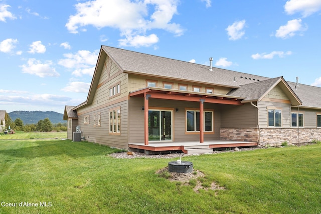 24 Bellflower, Blanchard, ID 83804 - rear view of house featuring an outdoor fire pit, a deck with mountain view, a yard, and roof with shingles