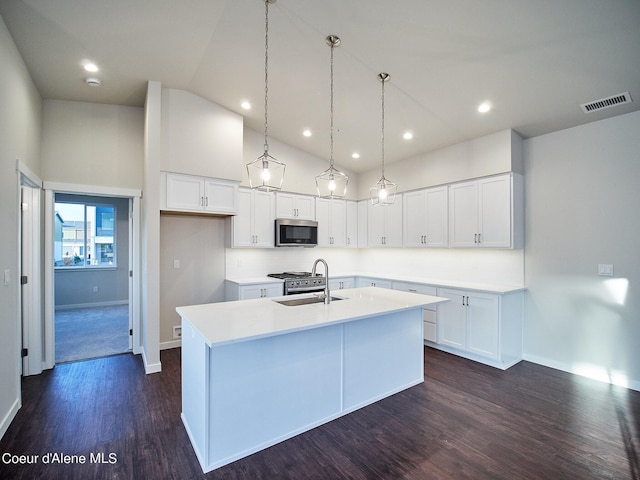 962 E Railroad Ave, Post Falls, ID 83854 - kitchen featuring stainless steel microwave, a kitchen island with sink, dark wood-type flooring, white cabinets, and light countertops