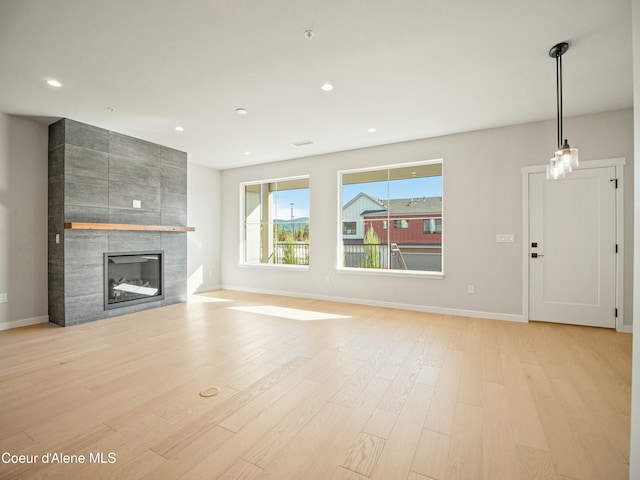 1033 E Railroad Ave, Post Falls, ID 83854 - unfurnished living room with light wood-type flooring, a tiled fireplace, and recessed lighting
