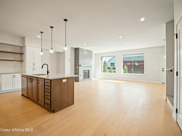 1033 E Railroad Ave, Post Falls, ID 83854 - kitchen featuring open shelves, light wood-style floors, white cabinets, tasteful backsplash, and a center island with sink