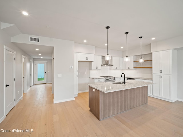 1033 E Railroad Ave, Post Falls, ID 83854 - kitchen with wall chimney exhaust hood, light wood-style flooring, white cabinetry, a kitchen island with sink, and recessed lighting