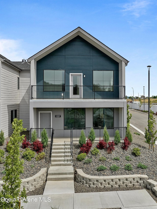 1037 E Railroad Ave, Post Falls, ID 83854 - view of front facade featuring a balcony, covered porch, stucco siding, and stairs
