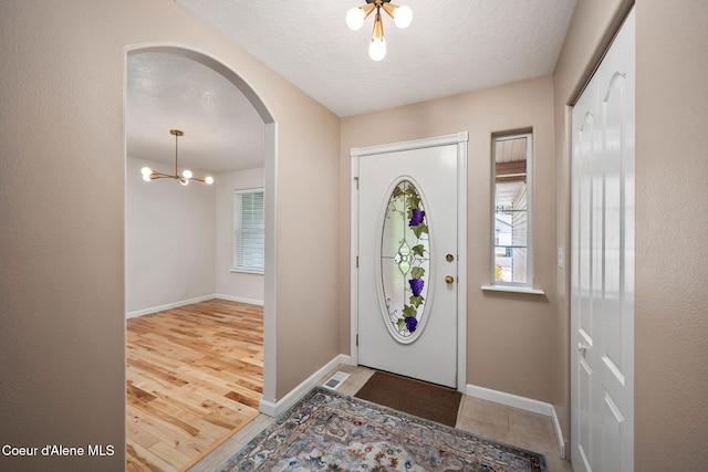 5188 E Twila Ct, Post Falls, ID 83854 - entrance foyer featuring arched walkways, a chandelier, a textured ceiling, and wood finished floors