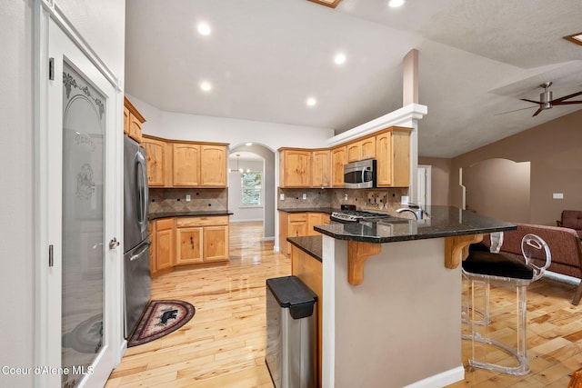 5188 E Twila Ct, Post Falls, ID 83854 - kitchen featuring stainless steel appliances, arched walkways, light wood-type flooring, a kitchen bar, and recessed lighting