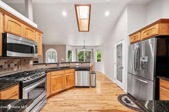 5188 E Twila Ct, Post Falls, ID 83854 - kitchen featuring appliances with stainless steel finishes, light wood-type flooring, decorative backsplash, a peninsula, and vaulted ceiling