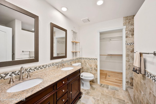5188 E Twila Ct, Post Falls, ID 83854 - bathroom featuring tile walls, double vanity, a wainscoted wall, a spacious closet, and recessed lighting