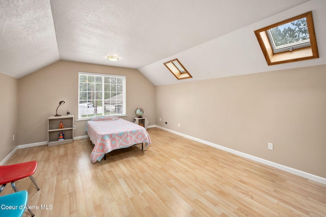 5188 E Twila Ct, Post Falls, ID 83854 - bedroom with a skylight, light wood-type flooring, lofted ceiling, and a textured ceiling