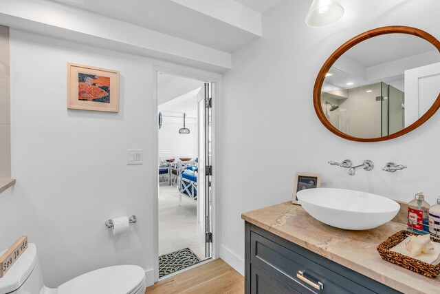 bathroom featuring vanity, hardwood / wood-style floors, an enclosed shower, and toilet