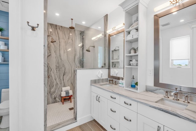 bathroom with vanity, hardwood / wood-style flooring, toilet, and tiled shower