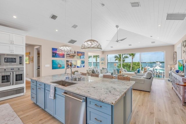 kitchen featuring sink, hanging light fixtures, stainless steel appliances, an island with sink, and white cabinets