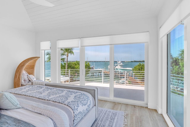 bedroom with a water view, access to outside, lofted ceiling, and light wood-type flooring