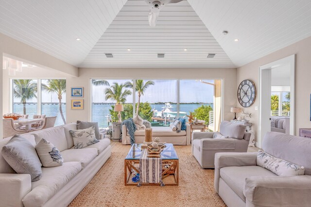 living room with vaulted ceiling, a healthy amount of sunlight, and a water view