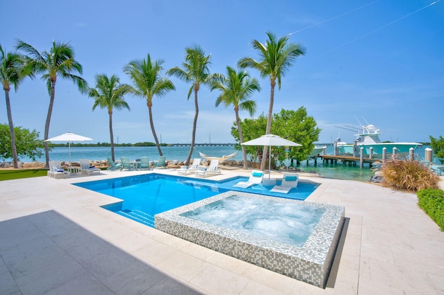 view of pool with an in ground hot tub, a water view, and a patio area