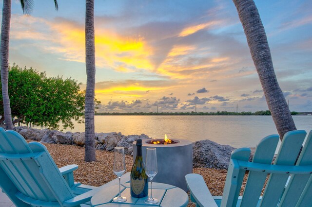 patio terrace at dusk with a water view and a fire pit