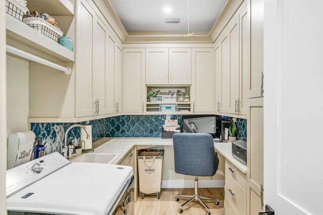 washroom featuring cabinets, sink, light hardwood / wood-style floors, and washer / clothes dryer