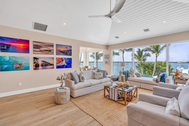 living room featuring vaulted ceiling, a water view, a wealth of natural light, and light hardwood / wood-style flooring