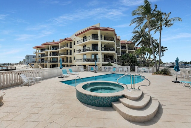 community pool featuring a patio, fence, and a hot tub
