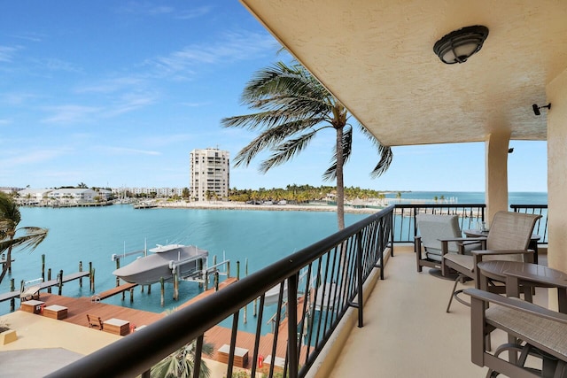 balcony with a water view, a dock, and boat lift