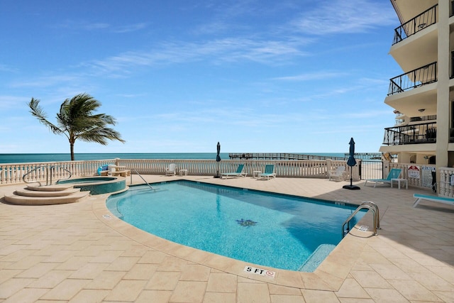 view of swimming pool with a patio area, a pool with connected hot tub, and a water view