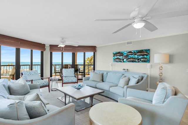 living room featuring visible vents, a water view, ornamental molding, ceiling fan, and light wood-type flooring