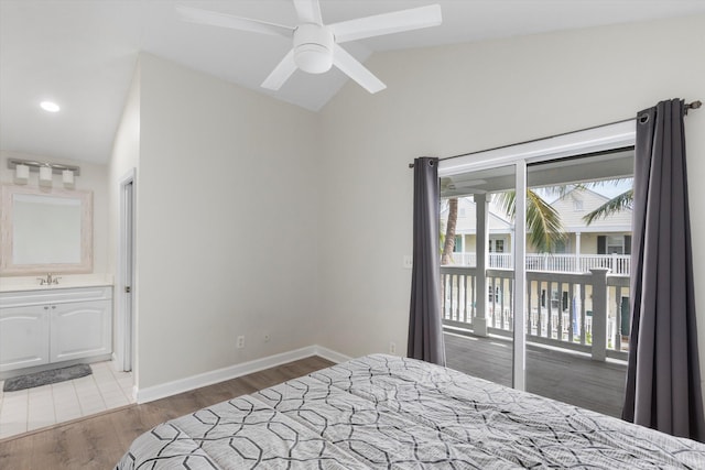 bedroom with sink, access to exterior, ensuite bathroom, wood-type flooring, and vaulted ceiling