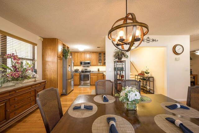 dining area featuring light hardwood / wood-style floors, a textured ceiling, and a notable chandelier