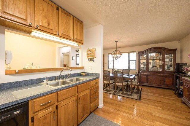 kitchen with sink, light hardwood / wood-style flooring, black dishwasher, a textured ceiling, and a chandelier