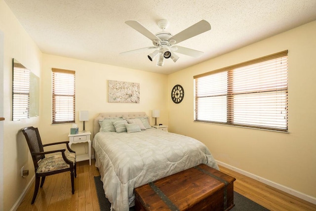 bedroom with ceiling fan, hardwood / wood-style flooring, and a textured ceiling