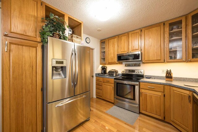 kitchen featuring appliances with stainless steel finishes, light hardwood / wood-style flooring, and a textured ceiling